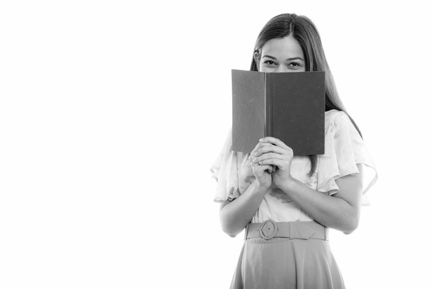 Estudio de la joven mujer hermosa escondida detrás del libro
 - Foto, Imagen