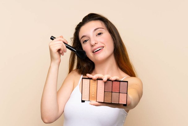 jong brunette meisje met make-up palet over geïsoleerde achtergrond - Foto, afbeelding