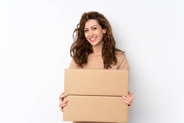 junge hübsche Frau mit isoliertem Hintergrund hält eine Schachtel, um sie auf eine andere Seite zu verschieben - Foto, Bild