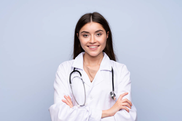 Young woman over isolated blue background with doctor gown - Фото, зображення