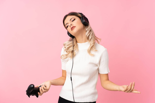 Teenager girl over isolated pink background playing at videogames - Foto, Imagem