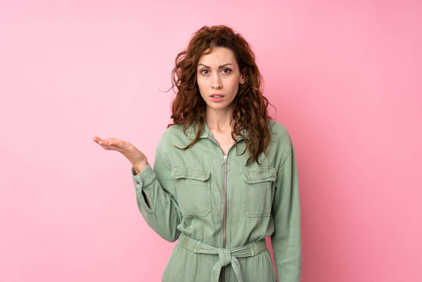 junge hübsche Frau über isoliertem rosa Hintergrund macht Zweifel Geste - Foto, Bild