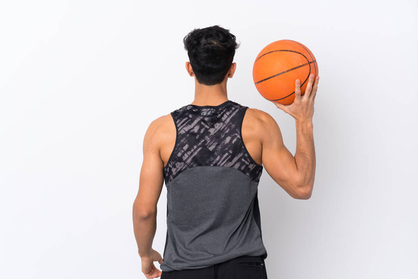 Young Argentinian man over isolated white background playing basketball in back position - Foto, immagini