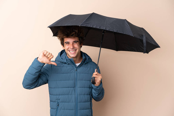 Άντρας που κρατάει ομπρέλα σε απομονωμένο φόντο περήφανος και αυτάρεσκος - Φωτογραφία, εικόνα
