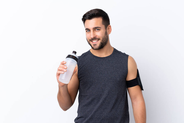 junger Sport schöner Mann mit Bart über isolierten weißen Hintergrund mit Sport Wasserflasche - Foto, Bild