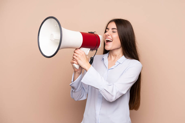 Young woman over isolated background shouting through a megaphone - Foto, Bild