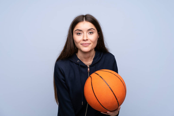 Young woman over isolated blue background with ball of basketball - Fotoğraf, Görsel