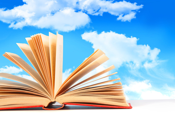 nyitott könyv egy kék ég ellen - Fotó, kép