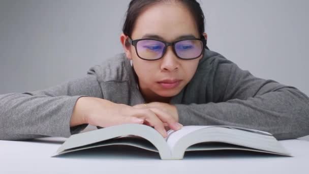 Jonge vrouw met een bril die een lijn trekt en een korte samenvatting schrijft tijdens het lezen van een boek in de bibliotheek. - Video