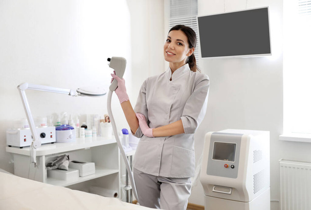 Young woman holding professional laser epilator in beauty salon - Zdjęcie, obraz