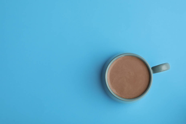 Delicious cocoa drink in cup on light blue background, top view. Space for text - Zdjęcie, obraz
