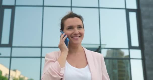 Adult business woman talking by mobile phone.  Smiling caucasian woman calling by  cell phone, outdoors. Happy lady  with mobile phone.  Real time. 4k. Business person talking by mobile phone. - Кадри, відео