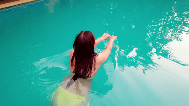 Kaunis nainen keltaisessa uimapuvussa uima-altaassa, ulkona - Materiaali, video