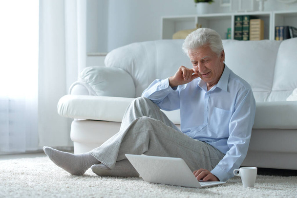  Emotionele senior man met laptop thuis - Foto, afbeelding