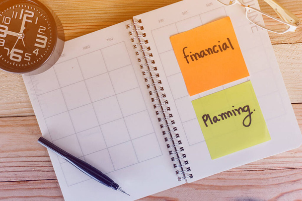 Concepto de planificación financiera, bloc de notas, moneda, vasos y despertador en mesa de madera
. - Foto, Imagen