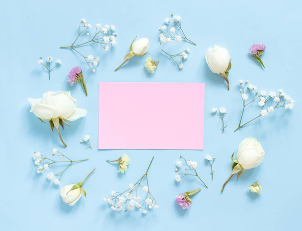Bloemen en roze papier op een lichtblauwe achtergrond - Foto, afbeelding
