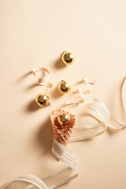 IJs wafel kegel met lint en ballen ornament topping. Huidkleur achtergrond  - Foto, afbeelding