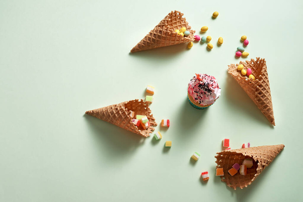 Quadro redondo de doces variados e cones de waffle com cupcake no fundo verde. Conceito de sobremesa. Deitado plano, vista superior - Foto, Imagem