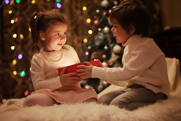 Familie op kerstavond bij open haard. Kinderen openen Xmas presenteert - Foto, afbeelding