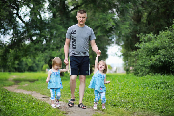 2人の娘の双子と一緒に公園を散歩 - 写真・画像