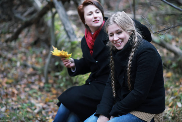 Pretty woman with teen daughter on a walk in the autumn garden - Photo, Image