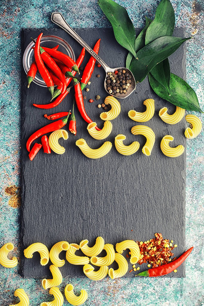 Uncooked pasta on a stone background. With seasonings and spices - Photo, Image