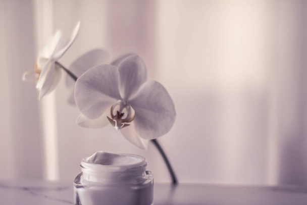 Face cream moisturizer jar and orchid flower, moisturizing skin  - Photo, Image