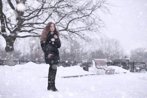 Girl in a winter park in snowfall - Photo, Image