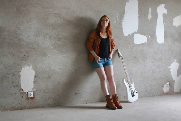 Jonge roodharige meisje met een elektrische gitaar. Rock muzikant gir - Foto, afbeelding