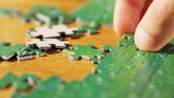 Caucasian male hands disassembling jigsaw puzzle. Single pieces and complete puzzle at background. Warm colors - Footage, Video