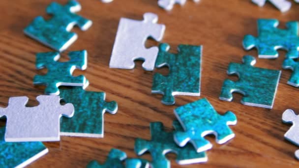 Panning from puzzle pieces to complete puzzle. Blue pieces on wooden table - Footage, Video