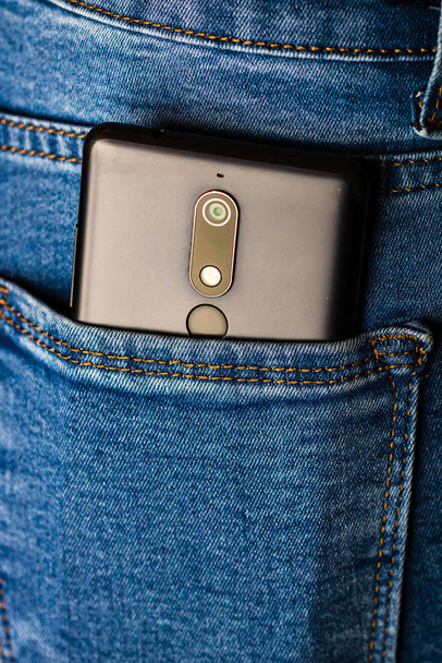 Cierre el teléfono inteligente en el bolsillo trasero de los jeans. Negocios y moda c
 - Foto, imagen