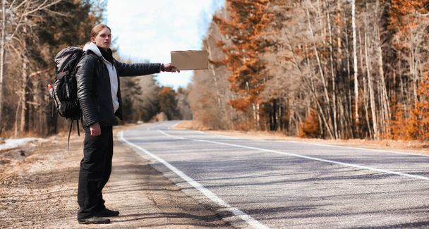 A young man is hitchhiking around the country. The man is trying - Photo, Image
