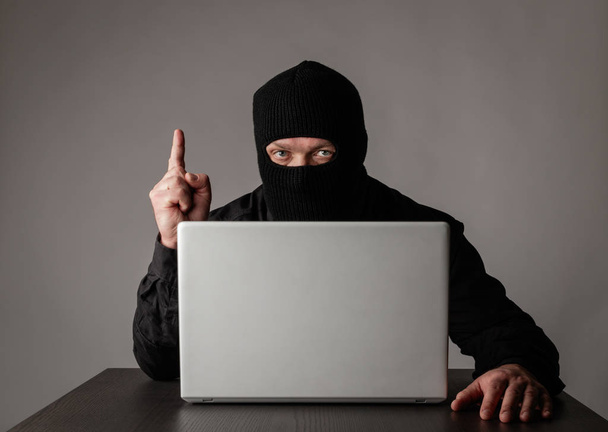 Hacker in mask using a laptop. - Φωτογραφία, εικόνα