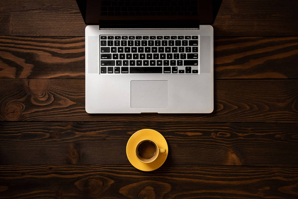 Caffè espresso in una tazza gialla vicino al computer portatile su uno schienale in legno gr
 - Foto, immagini
