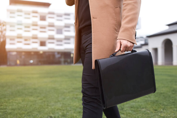  Επιχειρηματίας με καφέ παλτό και μια τσάντα με έγγραφα στα χέρια του πηγαίνει στο Wor - Φωτογραφία, εικόνα