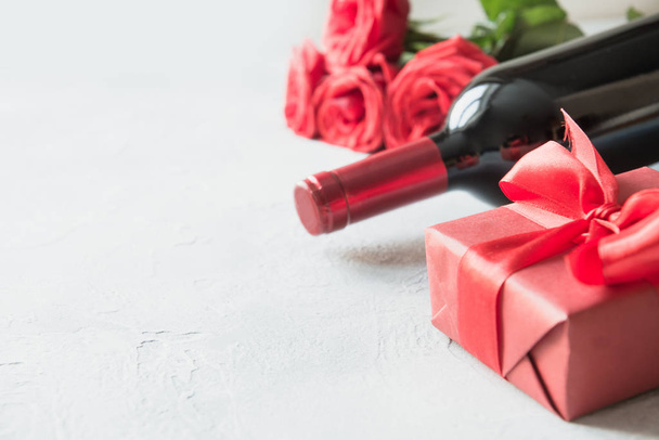 Valentines day greeting card with romantic red roses, bottle of red wine on white. Space for text. Close up. - 写真・画像