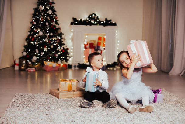 a boy with a girl open Christmas presents new year holiday Garland lights - Foto, Imagen