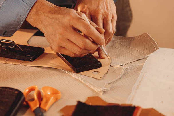 Leatherworker making a leather clothing with white fabric in a studio - Fotografie, Obrázek