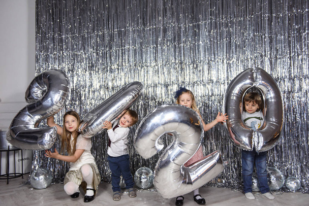 fröhliche Kinder haben Spaß mit Luftballons in Form von 2020 Jahr im neuen Jahr dekorativen Raum   - Foto, Bild