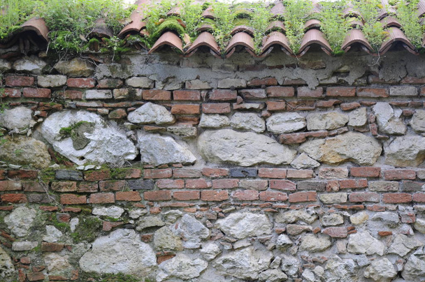 textuur di muro in mattoni e sassi con vecchie tegole di coccio - Foto, afbeelding