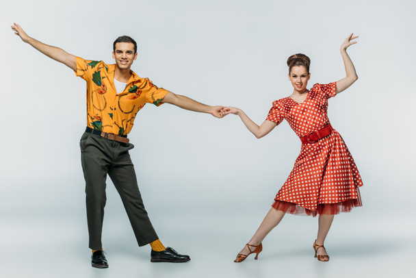 stylish dancers holding hands while dancing boogie-woogie on grey background - Photo, Image