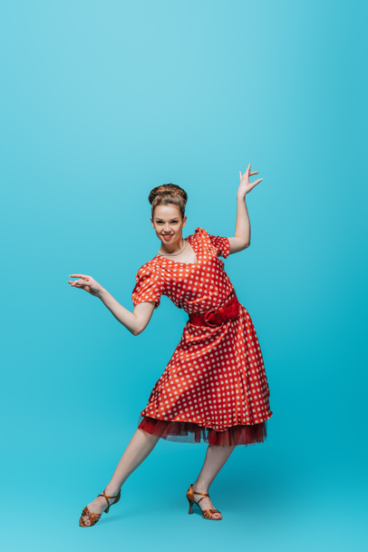attractive, stylish dancer looking at camera while dancing boogie-woogie on blue background - Фото, изображение