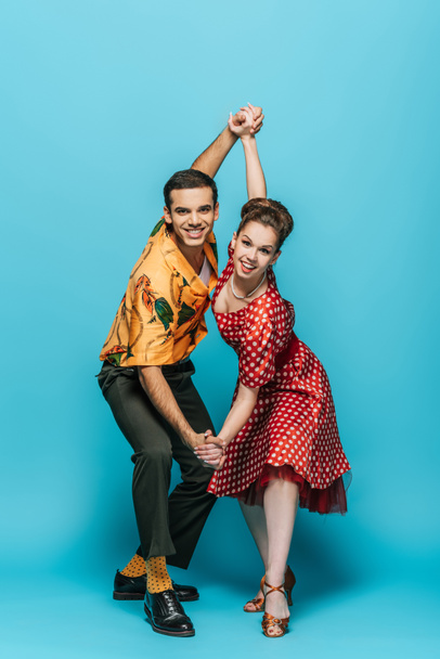 elegant dancers holding hands while dancing boogie-woogie on blue background - Foto, immagini