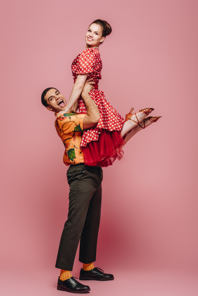 cheerful dancer holding partner while dancing boogie-woogie on pink background - 写真・画像