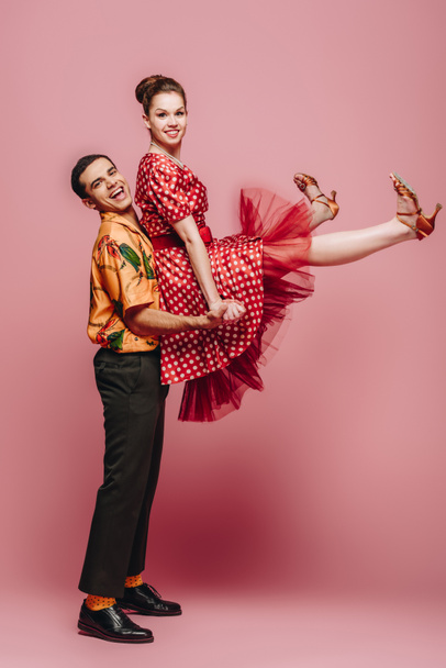 stylish man holding woman while dancing boogie-woogie on pink background - Valokuva, kuva