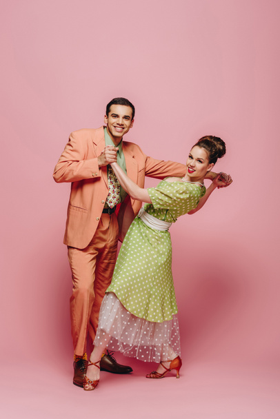 dançarinos felizes olhando para a câmera enquanto dançam boogie-woogie no fundo rosa
 - Foto, Imagem