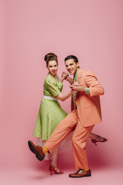 young dancers holding hands while dancing boogie-woogie on pink background - Foto, Imagem