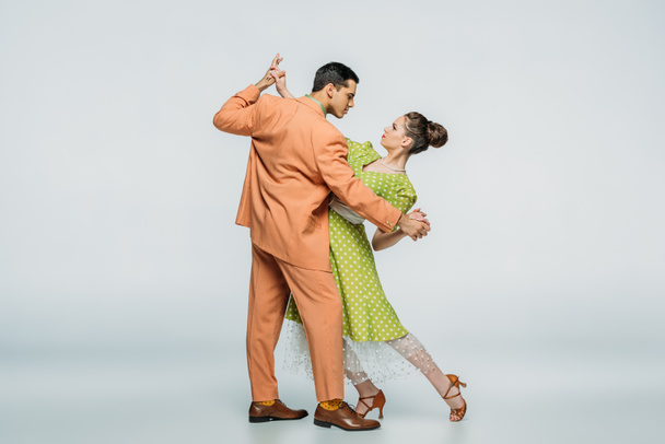 stylish dancers looking at each other while dancing boogie-woogie on grey background - Photo, Image