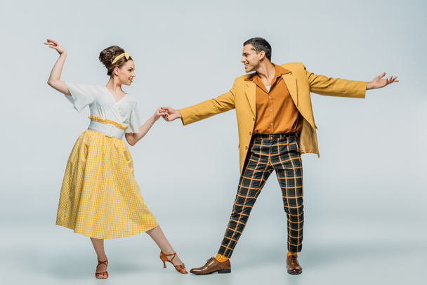 stylish dancers holding hands while dancing boogie-woogie on grey background - Photo, Image